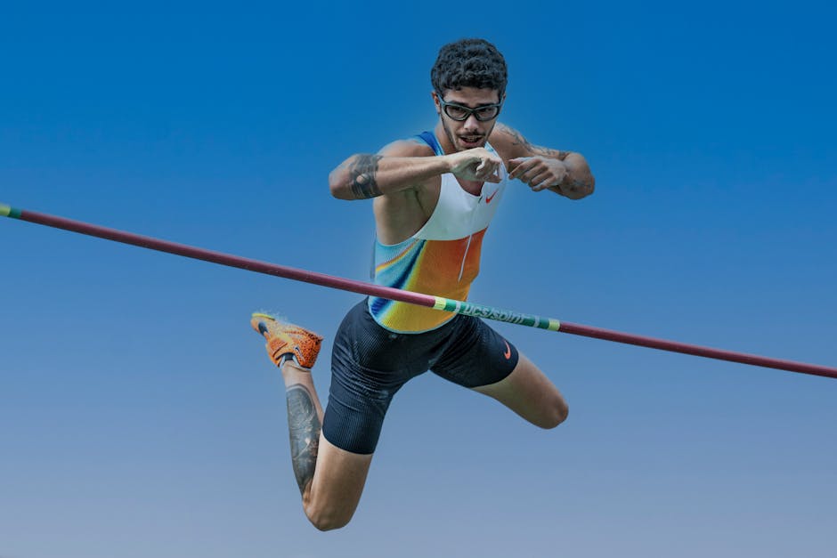 Athlete performing a pole vault jump, showcasing skill and athleticism against a clear blue sky.