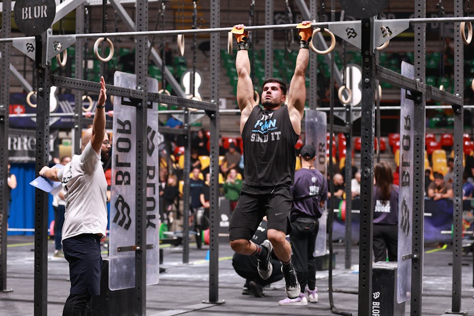 Athlete performing pull-ups during a competitive CrossFit event indoors