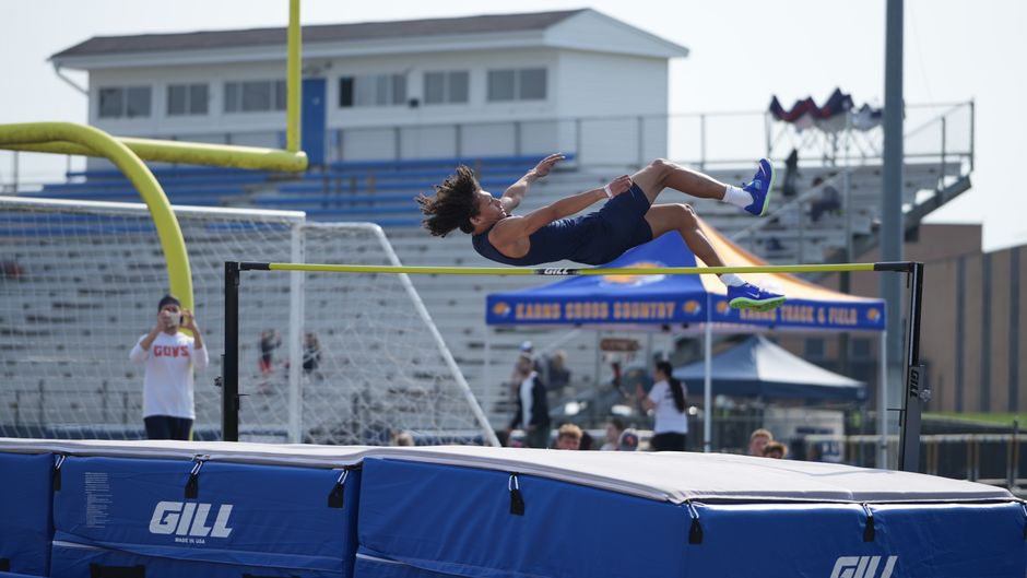 A young athlete clears the bar during a high jump at an outdoor track and field event.