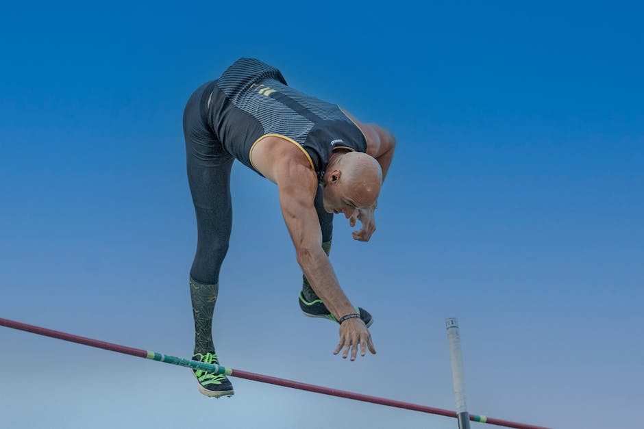Dynamic shot of an athlete skillfully clearing the pole vault bar under a clear sky