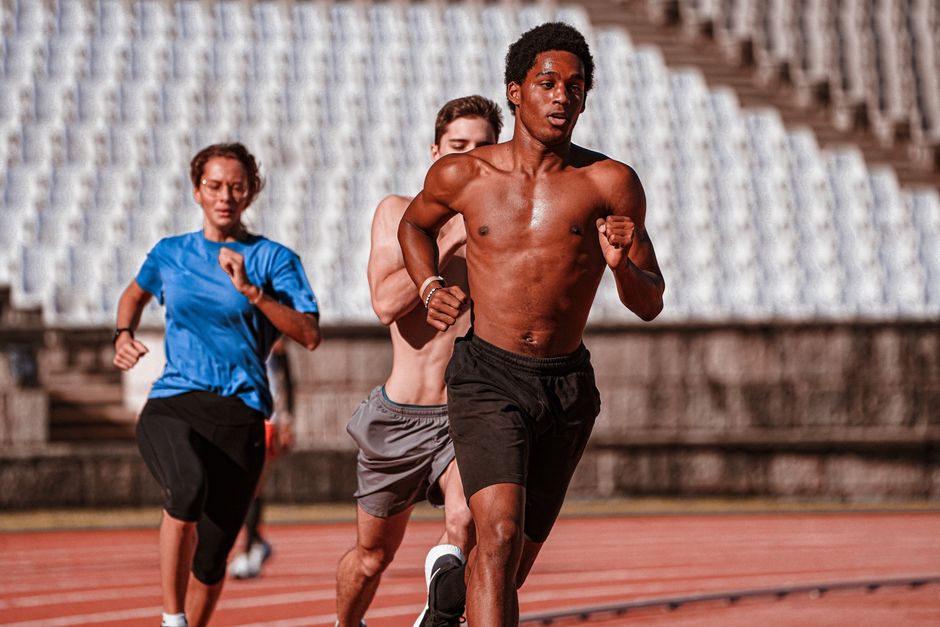Group of athletes training on an outdoor running track, showcasing fitness and determination.