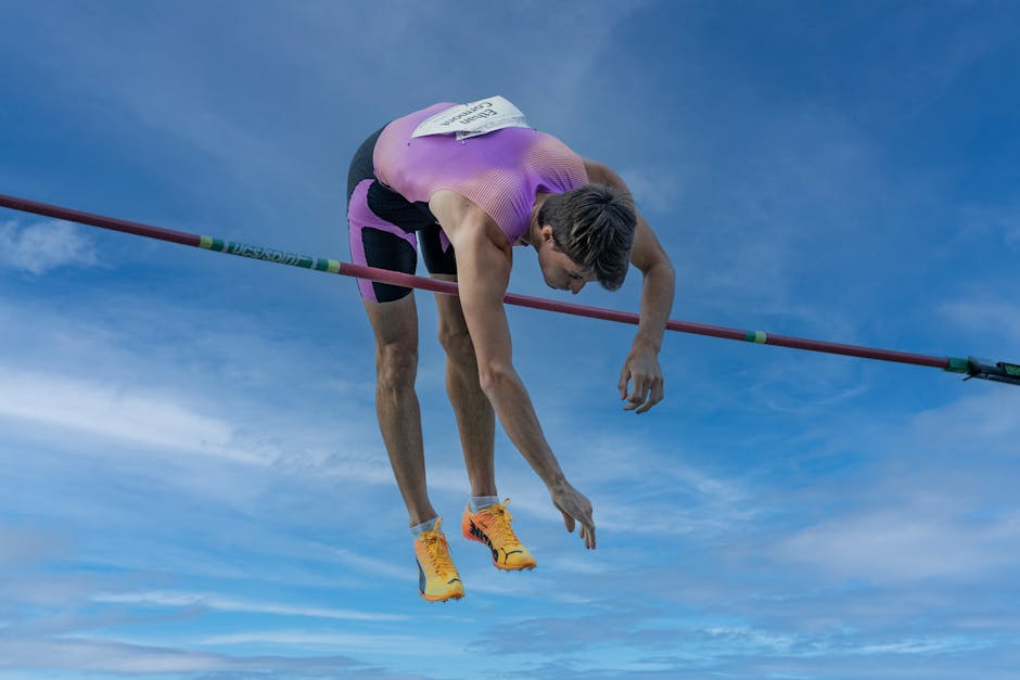 Dynamic capture of a pole vaulter clearing the bar under a clear blue sky