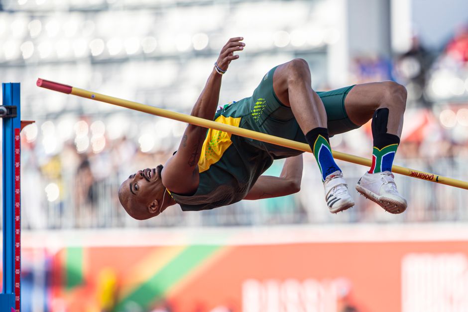 Athlete performing high jump outdoors in a stadium during a track and field event.