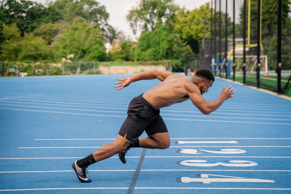 A male athlete intensely sprints on a vibrant blue outdoor running track