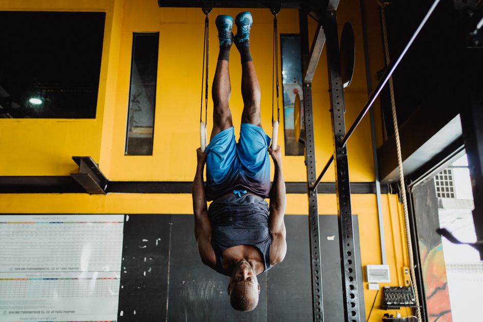 A man performs an inverted hanging exercise with gymnastic rings for fitness training.