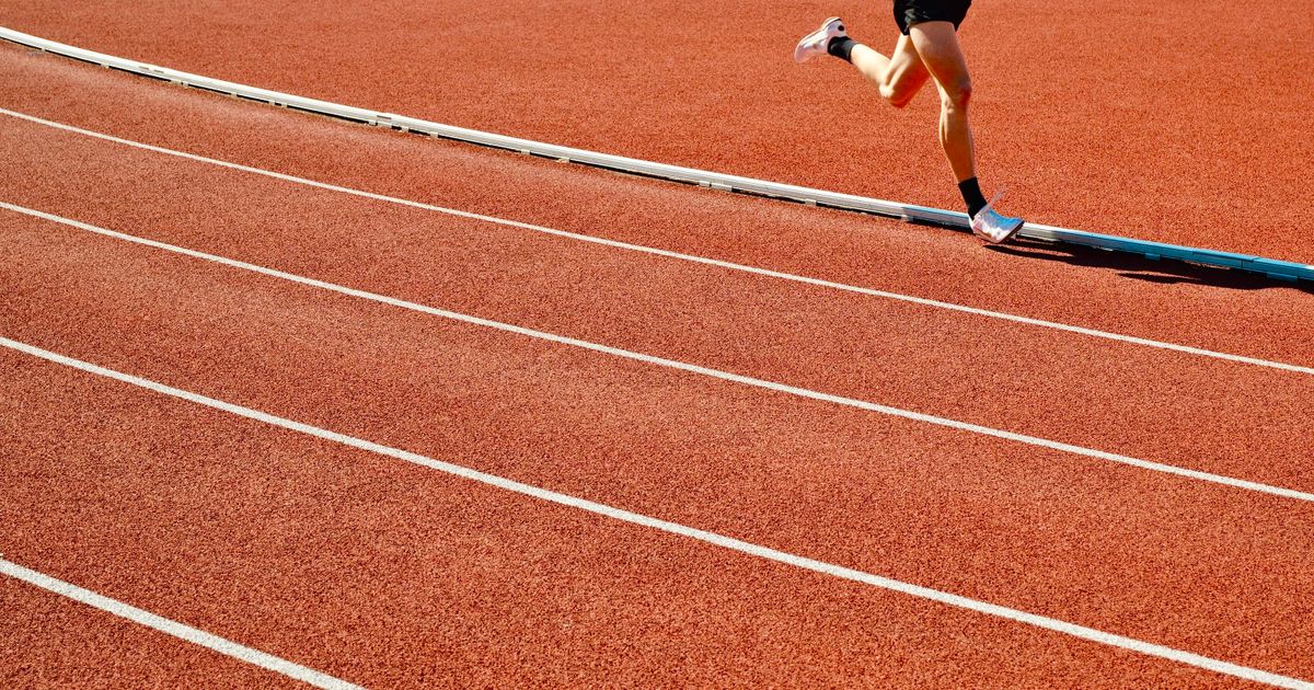 Athlete running on a red outdoor track at a stadium competition